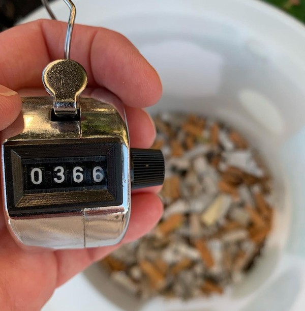 A counter displaying '366' with a bucket full of cigarette butts in blurred in the background A counter displaying '366' with a bucket full of cigarette butts in blurred in the background